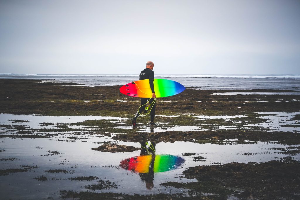 photo of surger with colorful surfboard, representing creativity, focus and hard work